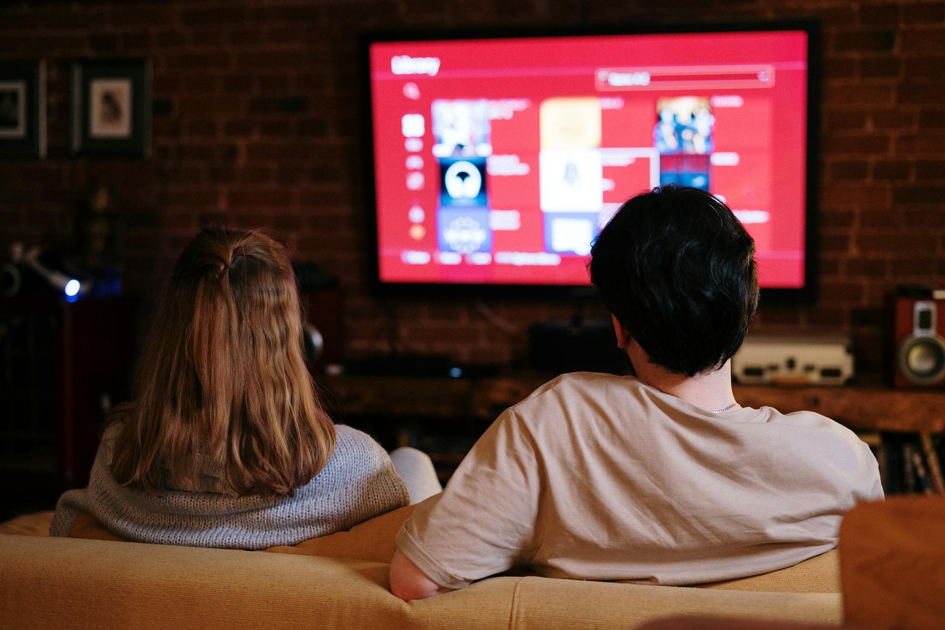 Photograph of a couple looking at a lit red screen in the background.