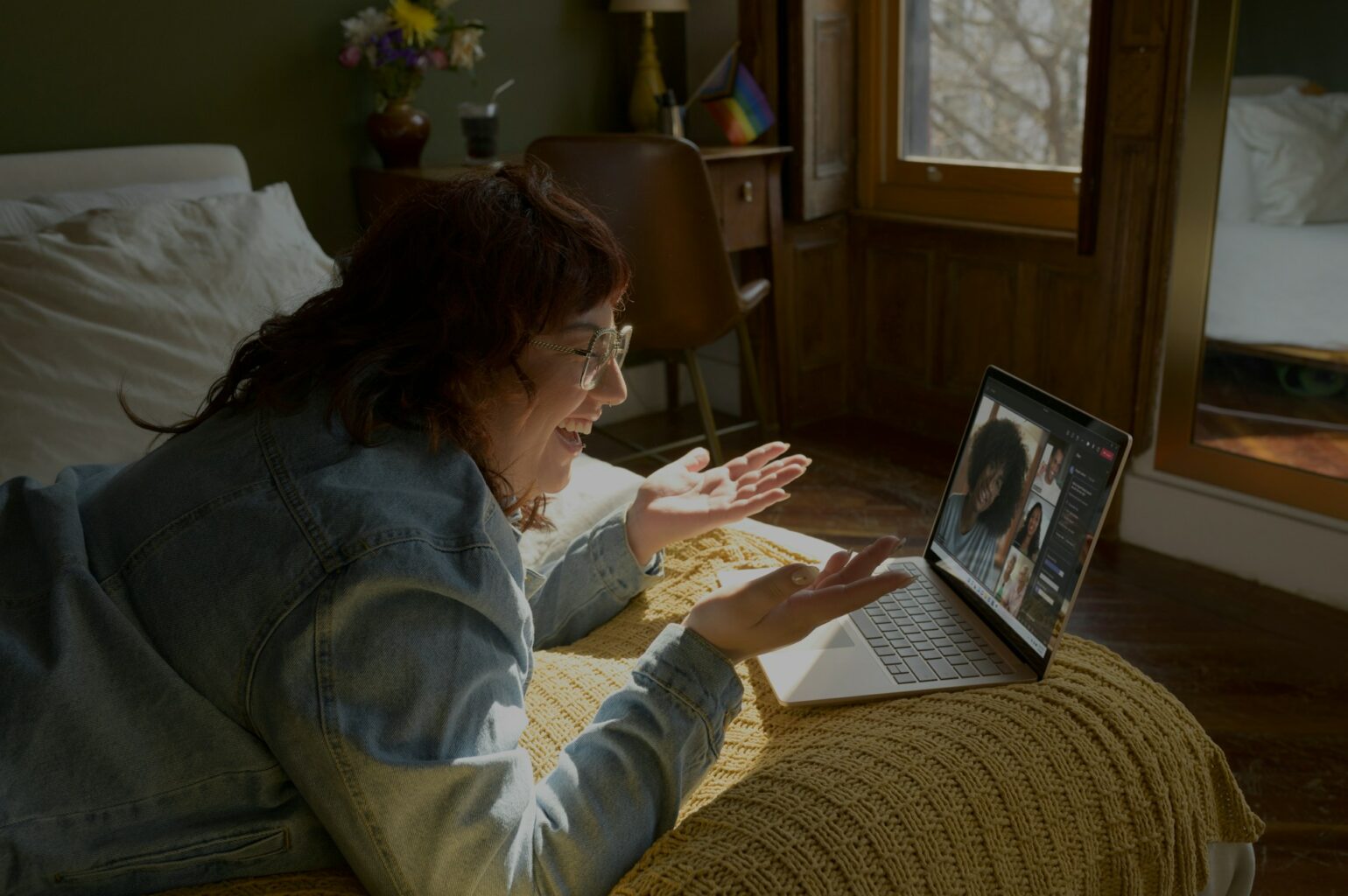 La fotografía muestra a una mujer trabajando en su Chromebook encima de su dormitorio mientras realiza una videollamada.