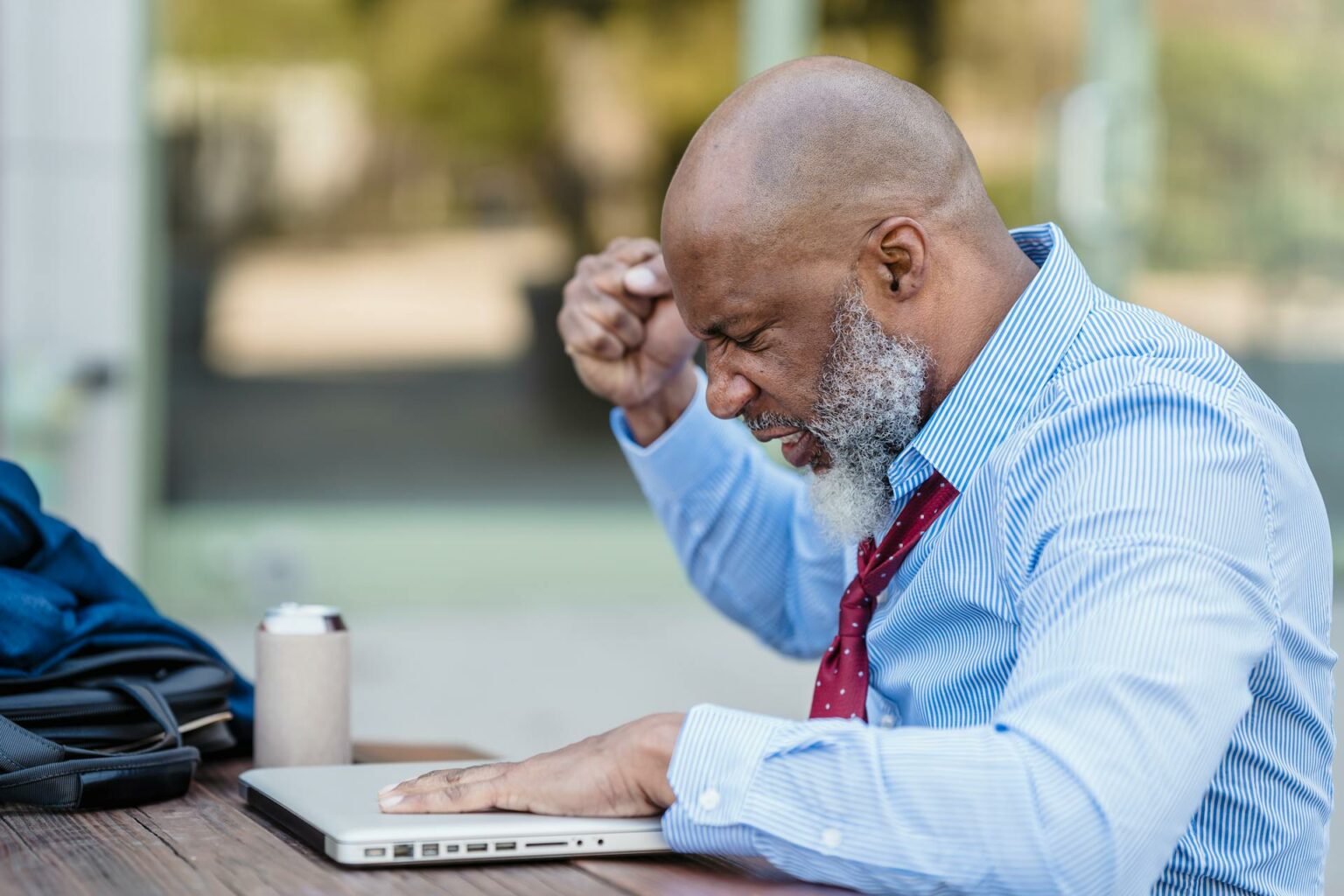 Photo of a man in blue shirt stressed in front of a computer.