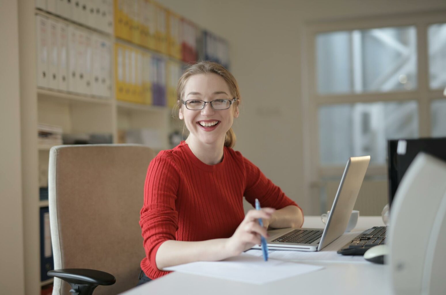 La fotografía muestra a una mujer navegando sonriente mientras trabaja en su ordenador.