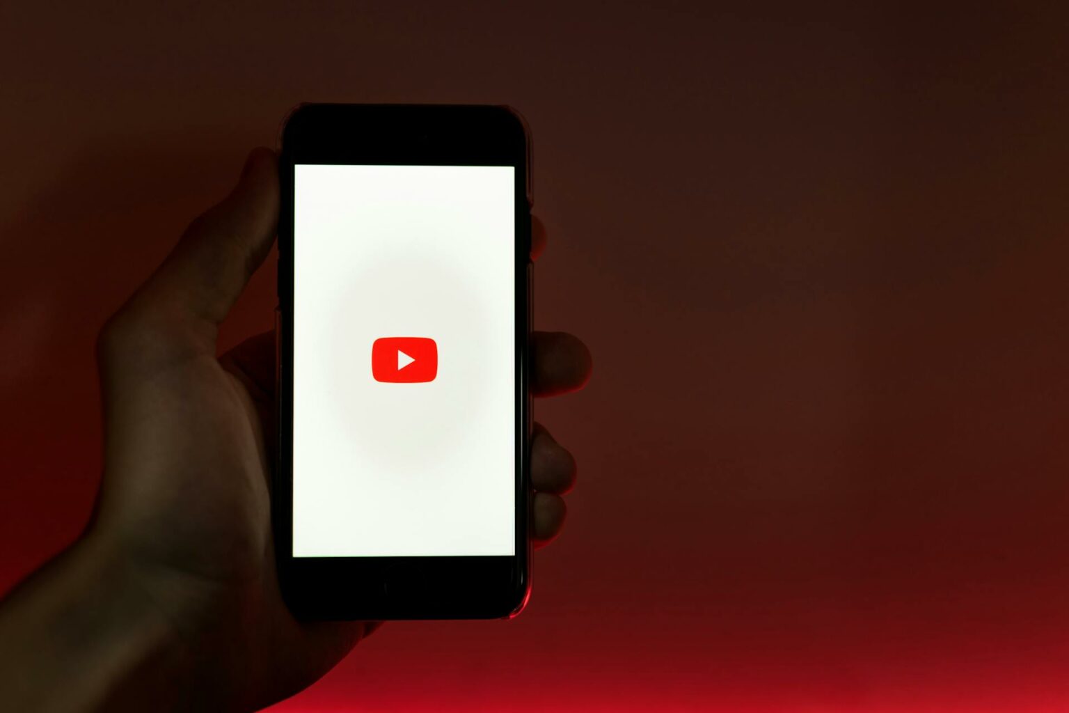 Fotografía que muestra a una persona sosteniendo su teléfono celular mostrando la aplicación de YouTube.